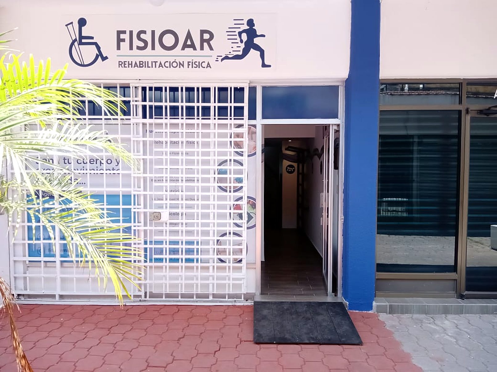 Fachada de la clínica FISIOAR Rehabilitación Física con su columna azul y el logotipo sobre la entrada